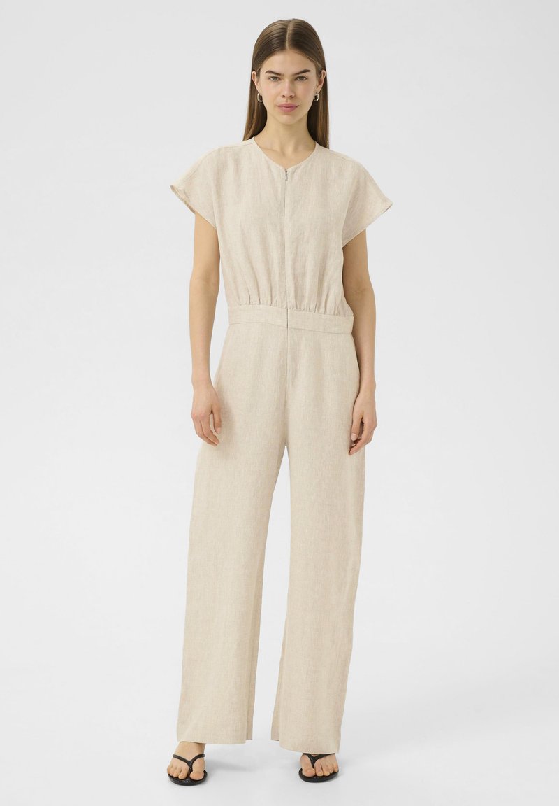 Combinaison en lin beige avec des manches courtes, un décolleté en V et une taille élastique. Le design présente des jambes larges et fluides ainsi qu'une texture douce.