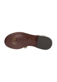 Sole di scarpa in pelle marrone con una finitura liscia, con tacco nero e marchio impresso. Le etichette forniscono informazioni su cura e taglie.