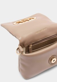 Beige faux læder håndtaske med guldtonet hardware-lukning, en lynlåslomme indeni og præget branding på forsiden.