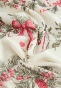 Tissu à motif floral en crème, avec un feuillage vert, des baies rouges et des nœuds roses. Texture douce avec un détail de drapé.