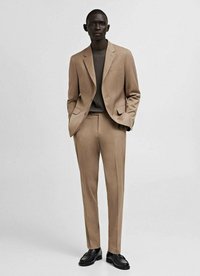 Bežna obleka s slim fit krojem, enojnim zapenjanjem in hlačami z ravnim sprednjim delom. Kombinirana s sivo srajco in črnimi čevlji, gladka tekstura tkanine.