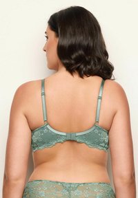 Spetsrygg-bh i dämpad grön, med justerbara satinband, vågiga kanter och blommönster. Slät finish med hakeförslutning.