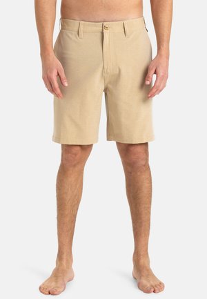 Beige shorts gemaakt van een zachte, gestructureerde stof. Ze hebben een knoopsluiting, een vlakke voorkant en steekzakken. Het ontwerp is casual en tot de knie.