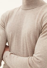 Beige turtleneck sweater i et blødt, tekstureret stof. Har lange ærmer med tætsiddende manchetter og viser et enkelt, strømlinet design.