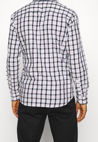 Camicia a maniche lunghe a quadri con motivo a griglia bianca, nera e rossa, con colletto classico e bottoni ai polsini.