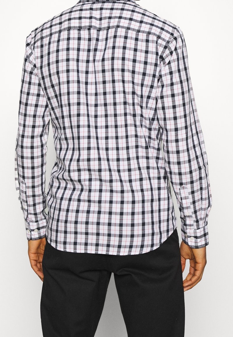Camicia a maniche lunghe a quadri con motivo a griglia bianca, nera e rossa, con colletto classico e bottoni ai polsini.
