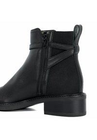 Bottines noires avec une tige en cuir, panneaux élastiques sur les côtés, tirette à l'arrière et un petit talon carré. Fermeture éclair sur le côté.