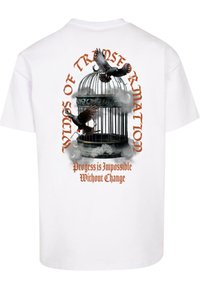 Hvid t-shirt med et grafisk motiv af et fuglebur med fugle i flugt. Teksten lyder "VINGER AF FORANDRING" og "Fremgang er Umulig Uden Forandring."