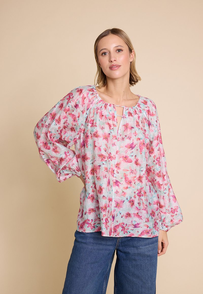 Blomstret bluse i let stof med et flerfarvet mønster i pink og blå. Lange ærmer med samlet halsudskæring og knapdetalje.