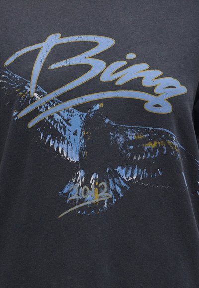 Κείμενο "Bing" με ένα στυλιζαρισμένο μπλε και κίτρινο αετό σε πτήση και το έτος "2013" από κάτω, τυπωμένο σε σκούρο ύφασμα.