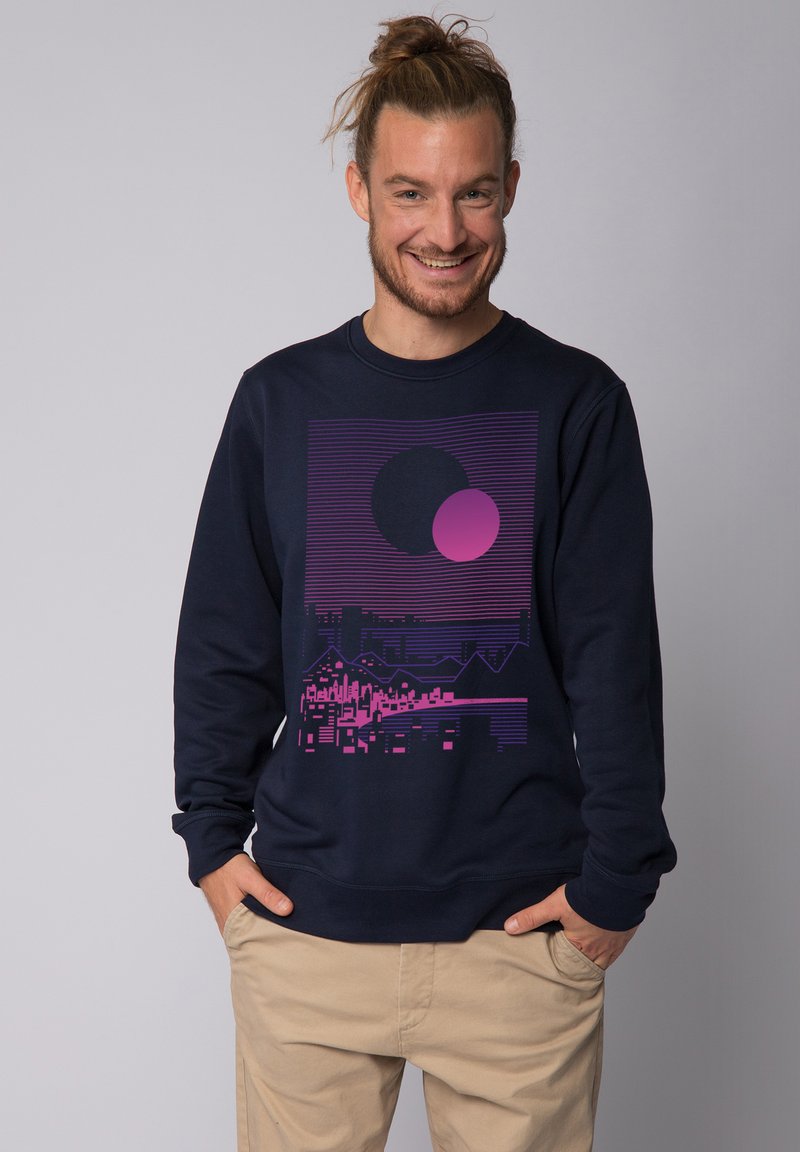 Marineblauer Sweatshirt mit grafischem Design, das zwei Kreise in Rosa und eine stilisierte Stadtlandschaft zeigt. Weicher Stoff, Rundhalsausschnitt und lange Ärmel.