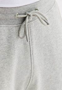 Jasnoszare dresy z ribbowanym pasem i przewiązanym sznurkiem widocznym w pobliżu przedniego szwu.