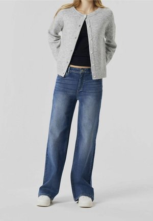 Szary sweter zapinany na guziki, czarna bluzka oraz szerokie niebieskie dżinsy, w zestawieniu z białymi trampkami. Gładka tekstura i swobodny design.