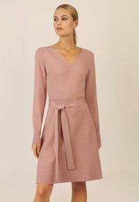 Strickkleid in sanftem Pink mit V-Ausschnitt, langen Ärmeln und Taillengürtel. Bietet eine lockere Passform und gerippte Akzente an den Bündchen und dem Saum.