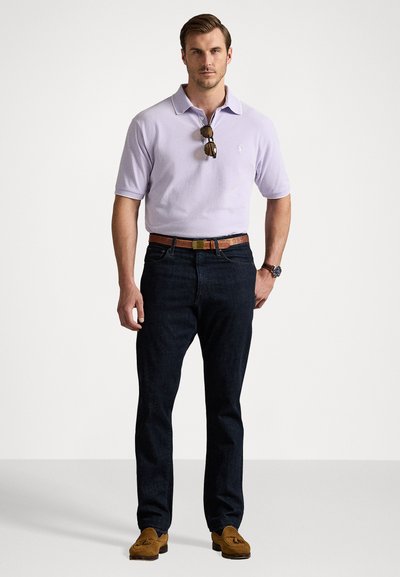 Ανοιχτό μωβ πόλο μπλούζα, σκούρο μπλε τζιν, καφέ δερμάτινη ζώνη και καφέ loafers. Γυαλιά ηλίου κρεμασμένα από το γιακά.