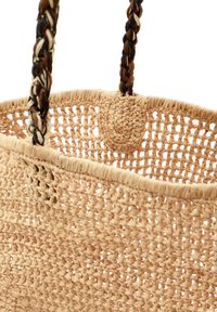 Borsa tote intrecciata in paglia con un colore beige naturale, caratterizzata da manici intrecciati scuri e chiari e un connettore rotondo nella parte superiore.