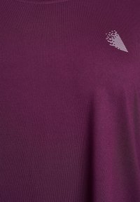 Ljubičasta kratkosleevesna košulja od glatkog materijala, s malim bijelim geometrijskim logotipom na lijevoj strani prsnog područja.