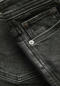 Černé džíny z denimu s úzkým střihem, viditelným šitím, kovovými detaily a malou přední kapsičkou.