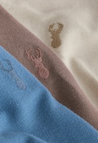 Strikket stof i creme, brun og blå striber med broderede hjortemotiver i brunt og blåt. Tekstureret overflade med en blød finish.