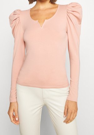 Haut à manches longues avec manches bouffantes en tissu rose pâle. Présente un décolleté en V et une coupe ajustée, avec des accents froncés sur les manches.
