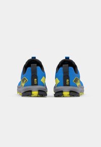 Chaussures de sport bleues avec des accents noirs, semelles jaunes, dessus texturé et intermédiaire gris. Présentent des languettes de tirage et un logo sur le talon.