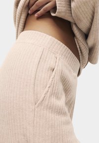 Béžový žebrovaný top a kalhoty na doma s jemnou texturou, s širokým pasem a bočními kapsami.