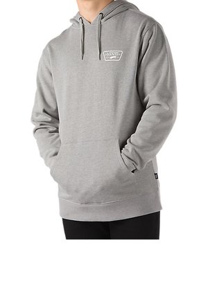 Homme portant un sweat à capuche Vans gris clair avec poche avant, cordons de serrage et petit logo sur le côté gauche de la poitrine, mains dans la poche.