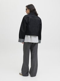 Black denim cropped jacket with a pointed collar, gray long-sleeve shirt underneath, and light gray wide-leg pants. Textured fabric details visible.