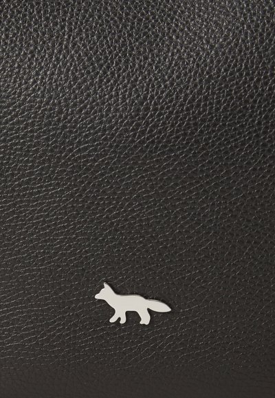 Musta tekstuuripinta nahka hopeasusiembleemiga. Pind näitab kivi- või papitüüpi mustrit, rõhutades materjali kvaliteeti ja detaile.