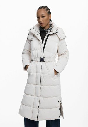 Manteau long blanc rembourré avec taille ceinturée, col haut, boutons pression et fentes latérales pour une aisance de mouvement. Tissu texturé avec une finition brillante.