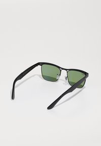 Ochelari de soare negri cu lentile pătrate, cu nuanță verde. Au un cadru metalic și brațe negre elegante. Include suporturi pentru nas ajustabile pentru confort.