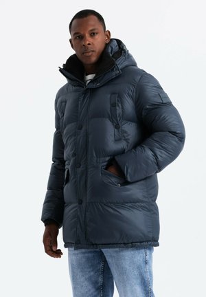 Chaqueta acolchada de color azul marino con capucha, con cierre de cremallera, múltiples bolsillos frontales y una textura suave y brillante.