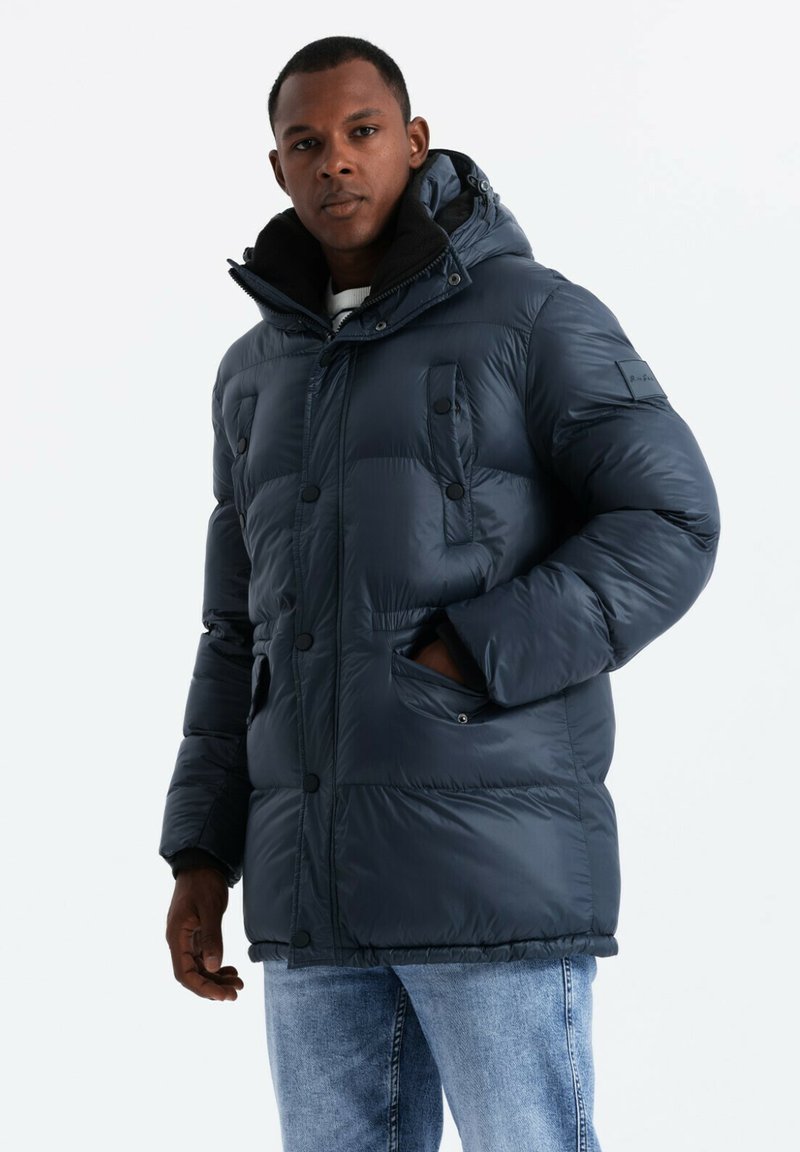 Giacca gonfiabile blu navy con cappuccio, caratterizzata da una chiusura con zip, numerose tasche frontali e una superficie liscia e lucida.