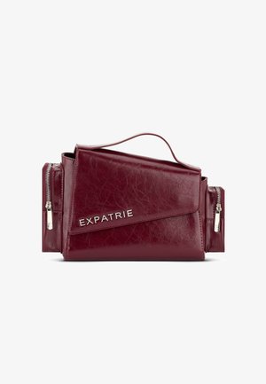 Bordeaux leren schoudertas met een flap aan de voorkant, zilverkleurige hardware, ritszakken en een geperst "EXPATRIE" logo op de voorkant.