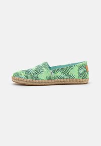 Espadrilha verde com padrão de folha de palmeira, parte superior em tecido e sola de corda de juta. Apresenta um pequeno laço de couro na parte traseira.