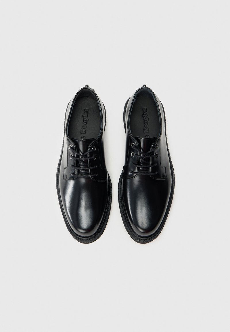 Black leather shoes with a smooth finish, round toe, and lace-up design. Features tonal stitching and black rubber sole.