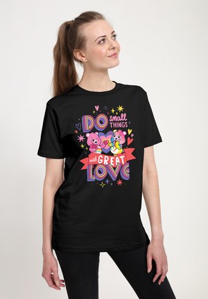 Sort t-shirt med et farverigt grafik, der viser to tegneserie-bjørne og teksten "Gør små ting med STOR kærlighed," akkompagneret af hjerter og stjerner.