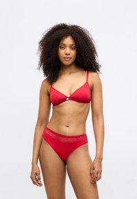 Rød lingerisæt bestående af en trekantsbh med en sølvspænde og matchende højtaljede trusser udsmykket med blomstret blonde.