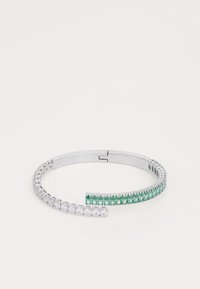 Bracelet jonc en argent avec un design incurvé, ornée de pierres précieuses claires et vertes disposées selon un motif gradué.