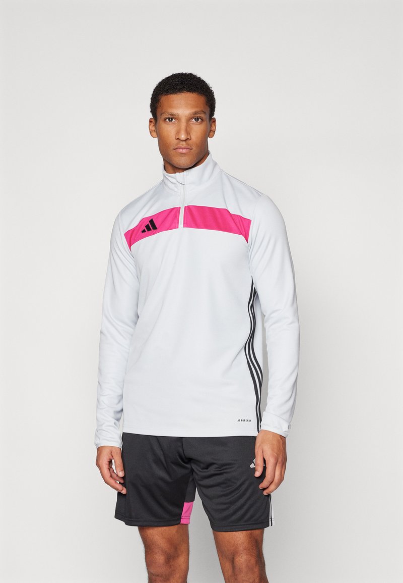 Haut de sport pour homme en gris clair avec un panneau rose et des accents noirs. Il possède un col à zip quart et un tissu texturé avec des manches longues.