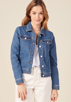 Chaqueta de mezclilla en azul medio con dos bolsillos en el pecho, cierre de botones y costuras en contraste. Mangas largas con un diseño de cuello clásico.