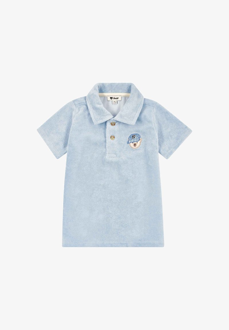 Polo bleu clair à manches courtes pour tout-petit, avec col, deux boutons et un petit patch en forme de visage d'ours portant une casquette rayée sur la poitrine.