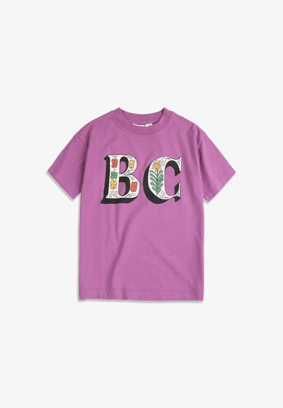 Lilla T-shirt med korte ærmer og store "BC"-bogstaver dekoreret med farverige blomster på forsiden.