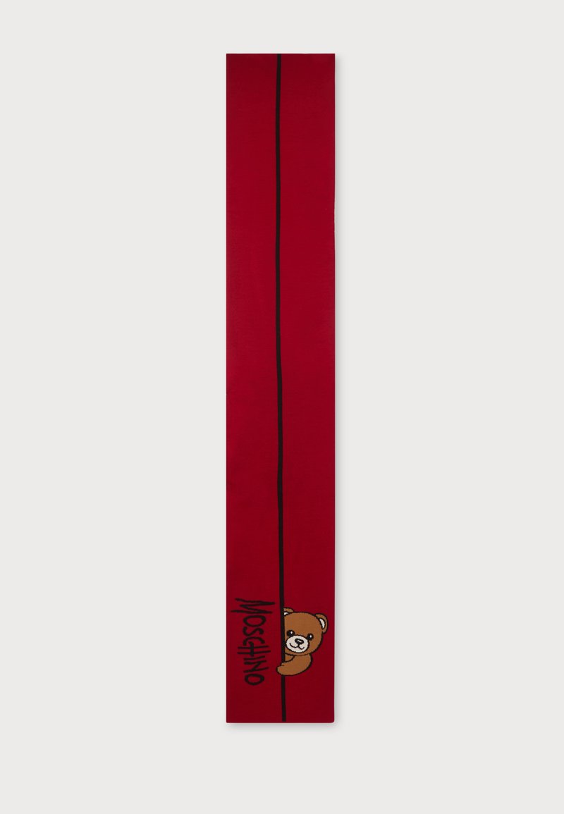 Longue écharpe rouge avec une ligne verticale noire près d'un bord et un ours en peluche qui dépasse au-dessus du mot Moschino en lettres noires.