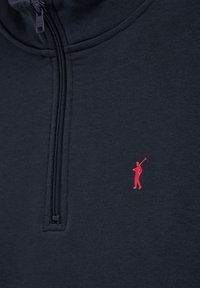 Marine kwart-rits fleece met een gladde textuur. Kenmerkt zich door een klein rood golffiguur logo op de linkerborst. Ritskraag.