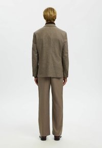 Brun rutete blazer og matchende bukser. Blazeren har én splitt og strukturerte skuldre. Glatt stoff med en skreddersydd passform.