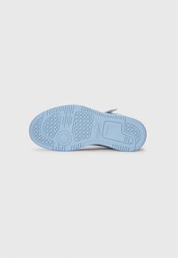 Semelle de sneaker bleu clair avec des motifs de grip texturés, présentant une découpe arrondie et divers designs de semelle pour une traction améliorée.