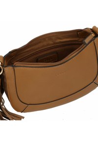 Bolso de hombro de cuero marrón claro con una textura suave, forma curva, un compartimento con cremallera y una etiqueta interior de marca. Presenta una correa desmontable.