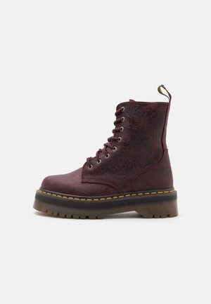Botte à plateforme bordeaux à lacets avec motif floral embossé, semelle épaisse en caoutchouc, surpiqûres jaunes et languette à l'arrière.