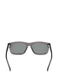Lunettes de soleil rectangulaires gris foncé avec des verres teintés et des branches fines noires, vues de face sur un fond blanc.